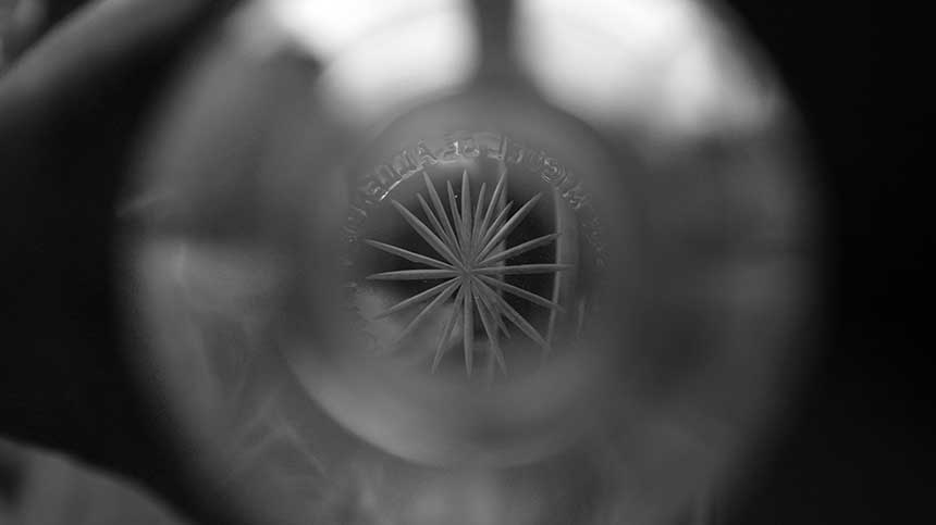 Peering through the top of a bottle, to see the engraving on the bottom.